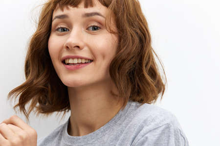 a happy, very joyful woman stands on a white background in a gray T-shirt smiling broadly expressing her emotions. Close horizontal photoの写真素材