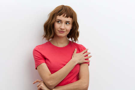 a beautiful, sweet, modest woman with red hair stands on a white background in a red cotton T-shirt...
