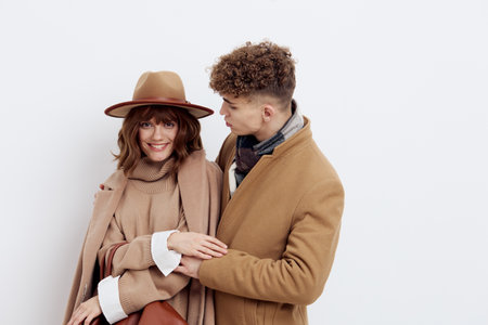 a happy couple a man and a woman are standing in stylish autumn clothes on a white background close to each other and a man looks tenderly at a womanの写真素材