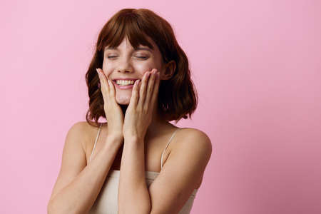 a close horizontal photo of a happy, attractive young woman on a pink background, smiling happily,...