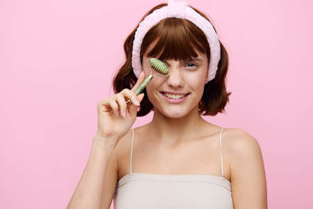 An emotional woman with clean skin, an ideal smile and dark beautiful hair stands on a pink...