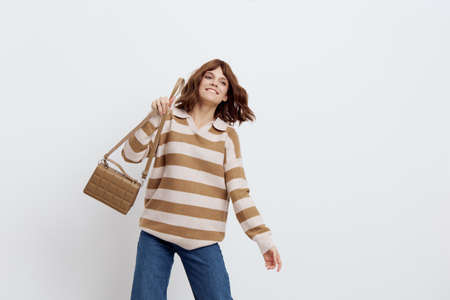 an admiring beautiful woman stands on a white background in a striped sweater smiling happily...