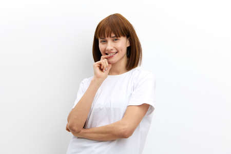 a beautiful, playful, thoughtful woman stands holding her finger near her mouth. Horizontal photo with an empty space for inserting an advertising layoutの写真素材