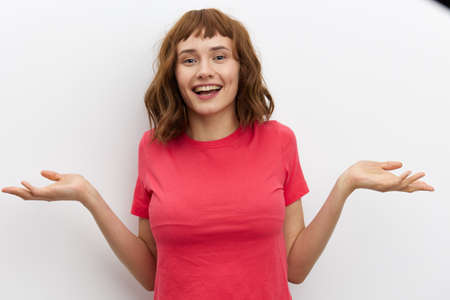 horizontal photo of a joyful, happy, laughing woman spreading her arms to the sides, standing on a white background with an empty space for inserting an advertising layoutの写真素材