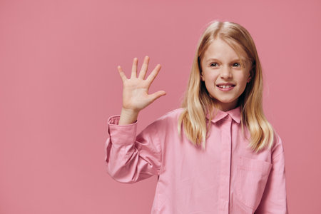 cute, beautiful, happy girl in pink clothes posing in the studio on a pink background showing five...