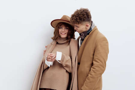 a sweet, beautiful, loving couple stands on a white background in stylish beige autumn clothes,...