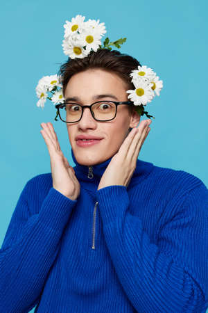 a handsome man in a blue zip-up sweater and black eyeglasses, standing on a light blue background...