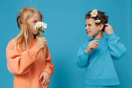 beautiful happy school-age children stand on a plain blue background in bright clothes, a girl...