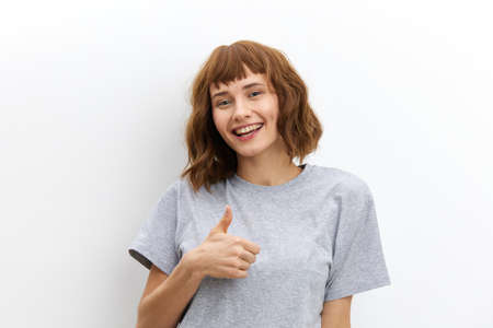 a happy, joyful woman with red hair and a beautiful hairstyle looks at the camera smiling and gives...
