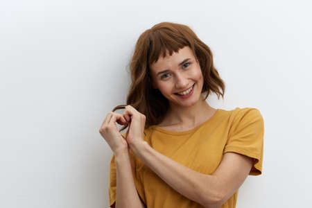 beautiful, attractive, redhead, romantic a woman poses standing in a yellow T-shirt on a white...