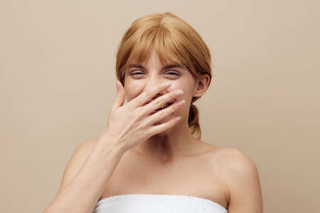 a pleasant, sweet, attractive woman with a short haircut stands on a beige background wrapped in a...
