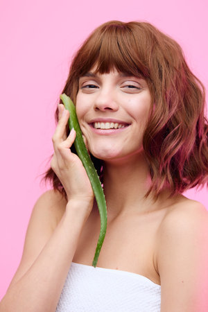 a close beauty portrait of a beautiful sophisticated woman with a beautiful styling, holding an aloe leaf near her face and smiling, squinting her eyes with pleasure,の写真素材