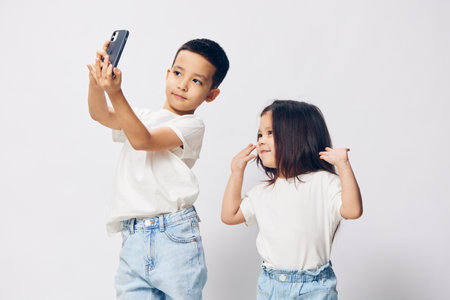 horizontal photo of happy, cute children, preschool age, brother and sister, in white shirts, taking...