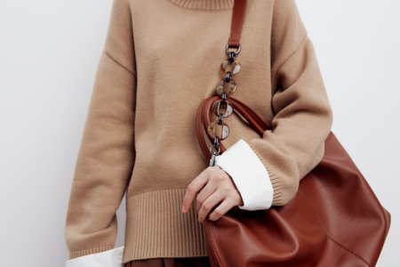 a woman holds a bag on one shoulder with her hand on it . Subject short-range shootingの写真素材