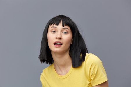 a happy, joyful woman stands on a gray background and smiles broadly looking into the camera with...