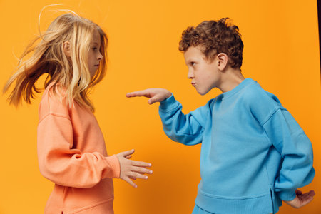 happy little children of school age stand in bright clothes on a yellow background and dance vigorouslyの写真素材