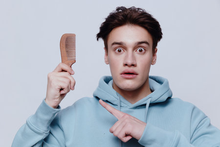 Horizontal portrait photo .a well-looking surprised young man in a light light blue hoodie, with a...