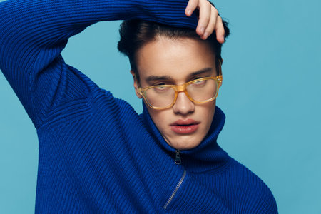 a close horizontal photo of a cute, handsome man in yellow sunglasses and a blue sweater, holding...