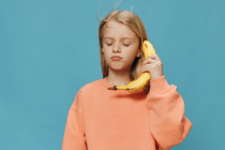 a cute, beautiful, funny girl is standing in an orange sweater and pretending to be talking on a...