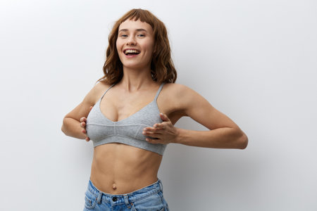 a happy, joyful woman stands on a bright background in stylish summer clothes and holds her hands on her chest, smiling broadlyの写真素材