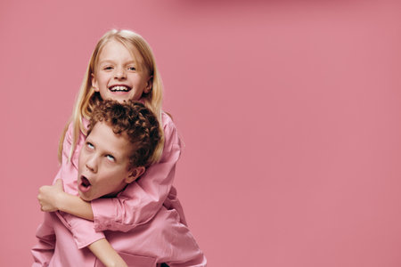 funny, happy kids brother and sister are playing and the boy is rolling the girl on his back making a funny face. Relationships, friendship, familyの写真素材