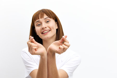 a happy, sweet, inspired red-haired woman stands on a white background in a white T-shirt and,...