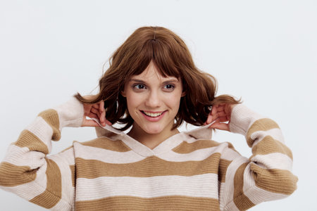 a sweet, pleasant woman with a short haircut stands on a light background in a stylish beige sweater and pulling back the neck poses relaxed with her eyes closedの写真素材