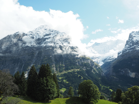 Snowy mountain peak covering up by cloud on a sunny dayの写真素材