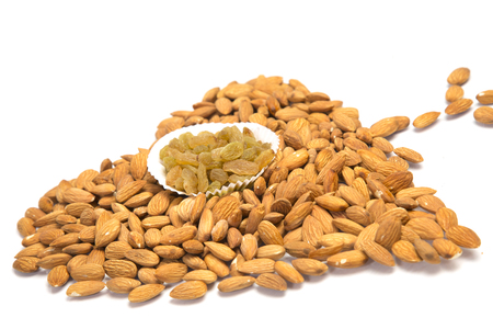 Almonds heart close-up pose with raisins. Isolated on white background.の写真素材