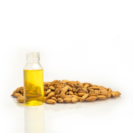 Almond nut heap with almond oil/roghan in bottle isolated on white background.の写真素材