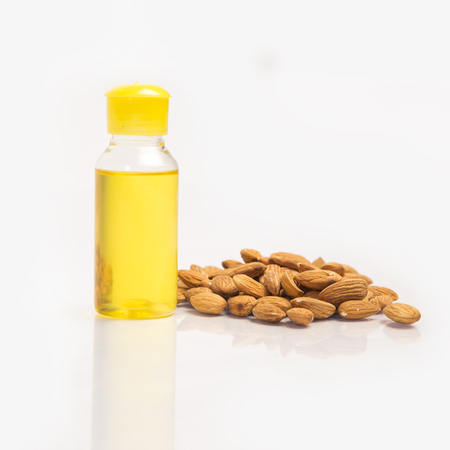 Pile of  dry almonds nut, oil in bottle and closed lid. isolated on white background.の写真素材