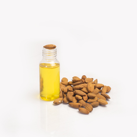 Almond oil bottle/roghan with almonds heap on white background.の写真素材