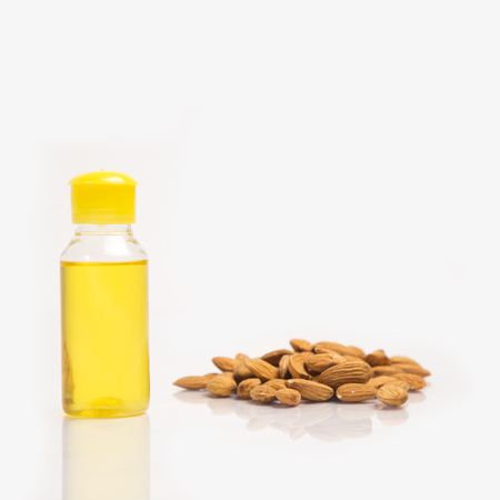 Pile of almonds, oil in bottle and closed lid. isolated on white background.の写真素材