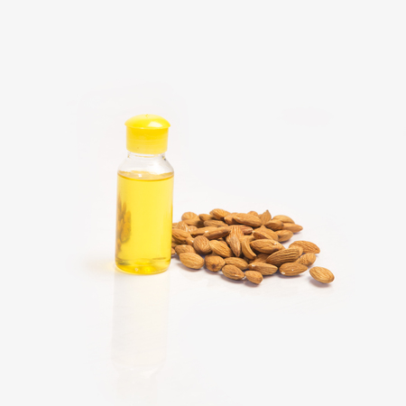 Pile of almonds with oil in bottle on white background.の写真素材