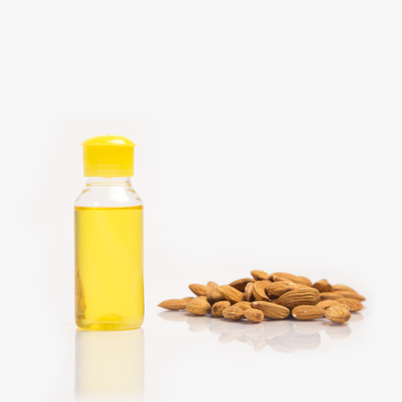 Almond heap with oil / roghan bottle on white background.の写真素材