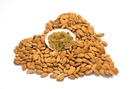 Dried almonds in heart shape with raisins. Isolated on white background.の写真素材