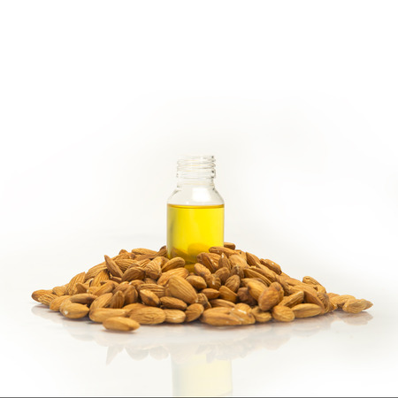 Pile of almonds with almonds oil / roghan in bottle. isolated on white background.の写真素材