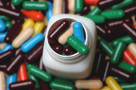 Top side closeup of Ayurvedic vitamin capsule with white bottle on wooden background.の写真素材