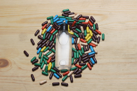 Top view of Ayurvedic capsule with transparent oil bottle on wooden background.の写真素材
