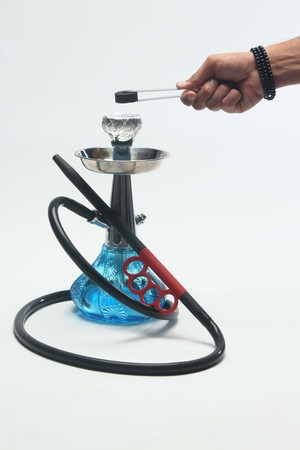 Glass Blue hookah and man hand holding a coal  with silver color tongs . Isolated on white...