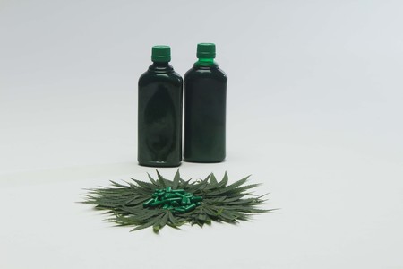 Green tablets, two bottle and marijuana leaves on white background.
