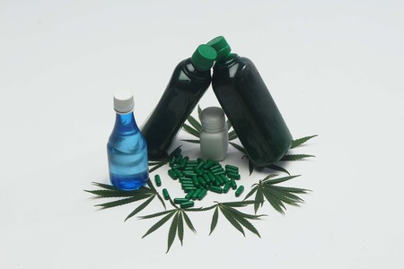 Decoration of marijuana leaves, Ayurvedic green tablets, hemp oil and medicine bottles.Isolated on white background.の写真素材