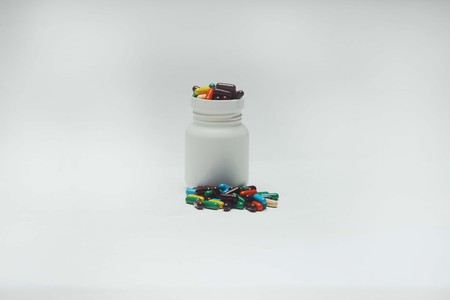 Colorful vitamin capsule with bottle. Isolated on white background.