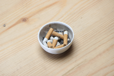 Cigarette in white ashtray on wooden background.の写真素材