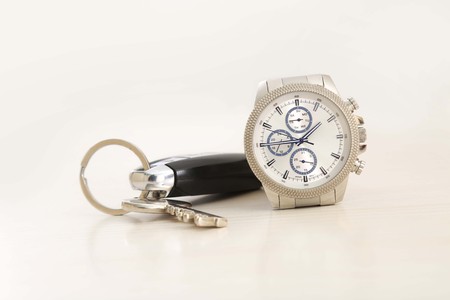 Picture of wrist watch and car key on white background.