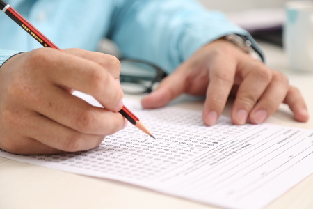 Man hand holding pencil. Man hand on OMR sheet.の写真素材