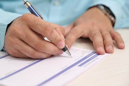 Man is filling form with pen.