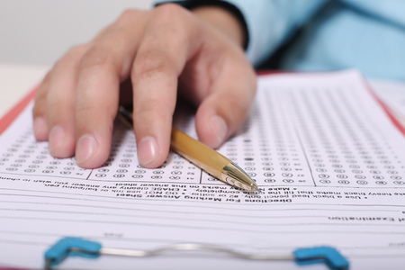 Picture of hand and pen on the OMR sheet with clipboard.の写真素材