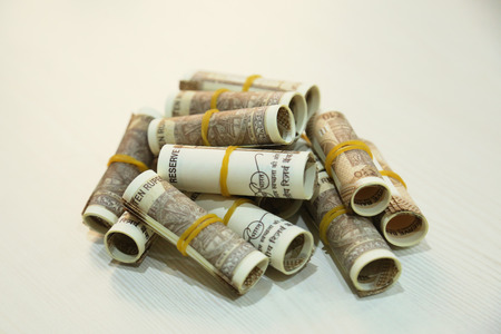 Rolls of Indian 10 rupee currency note stack on the wooden table.の写真素材