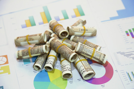 Stack of Indian 10 rupee currency note rolls on the chart paper.